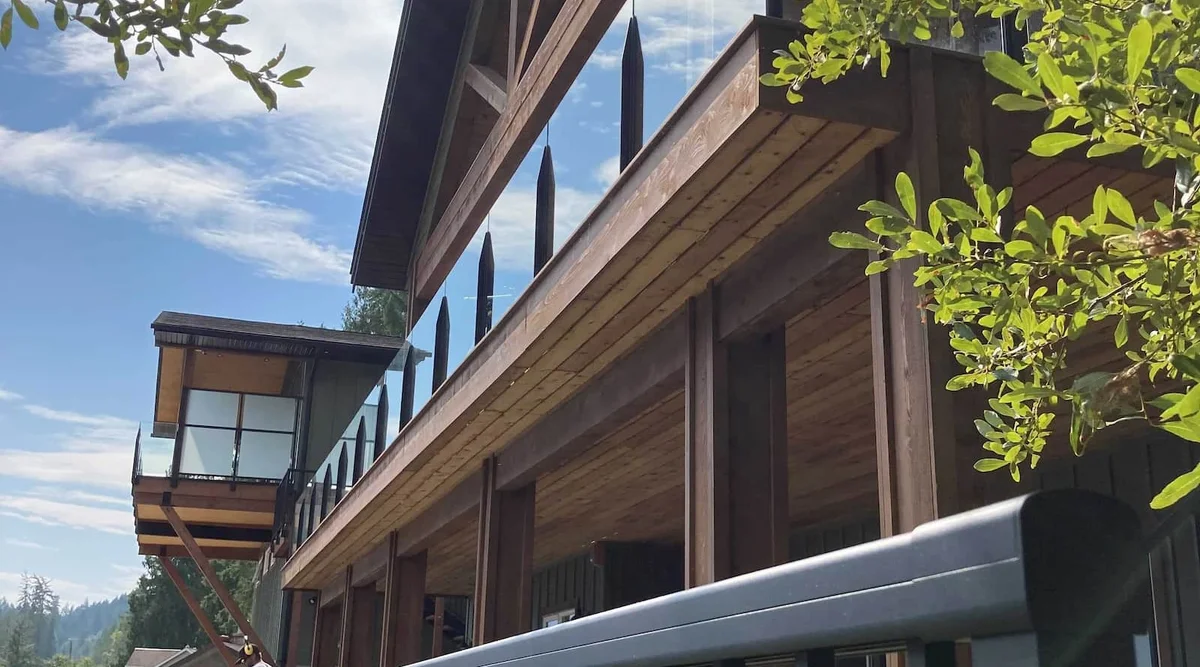 Two-storey timber frame home in Christina Lake, BC featuring black aluminum picket railing on the lower level and frameless infinity glass railing on the upper balcony