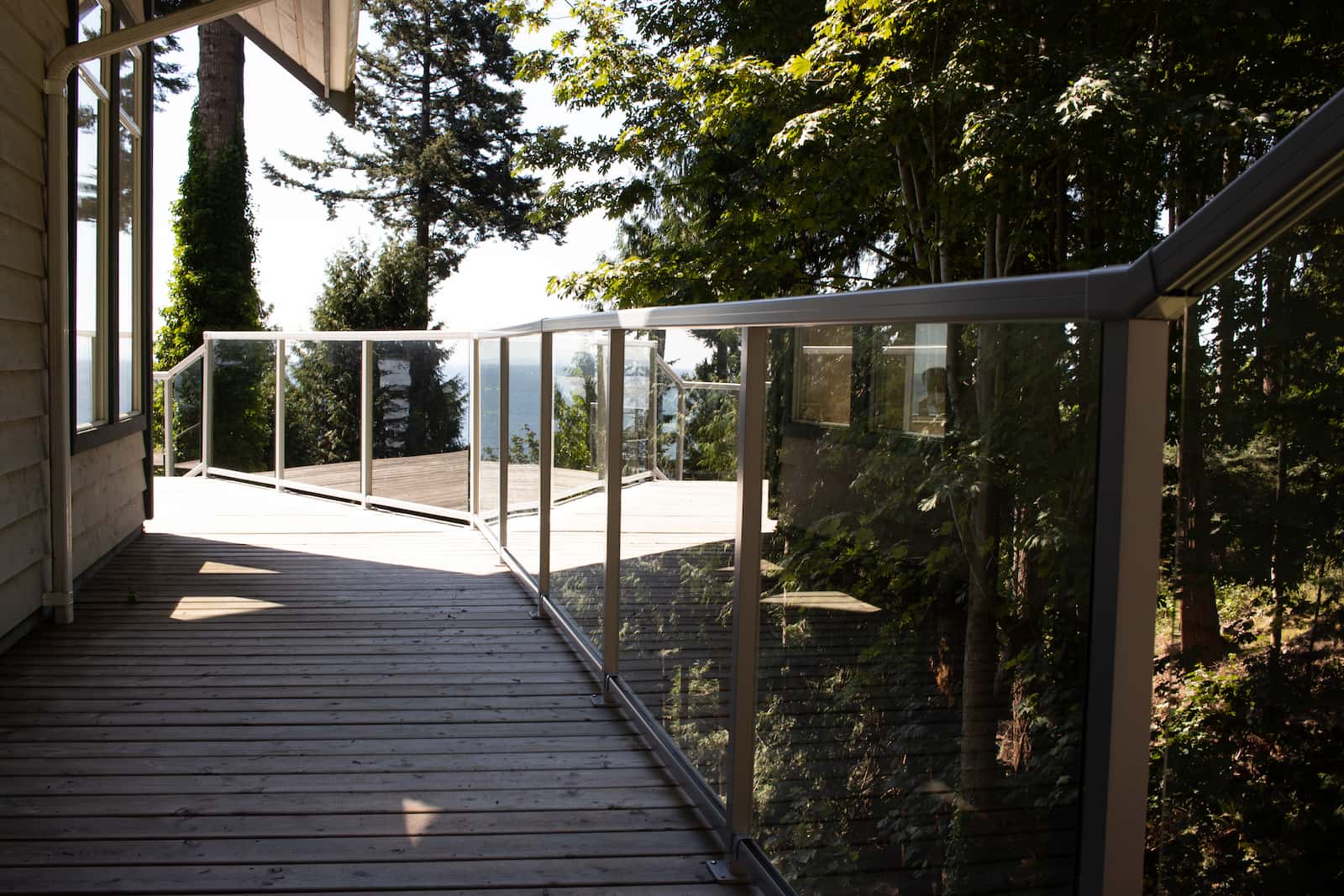 Glass component railing on a multi-level coastal deck with stair transitions and ocean views on the BC Sunshine Coast