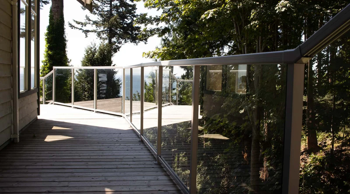 Glass component railing on a multi-level coastal deck with stair transitions and ocean views on the BC Sunshine Coast