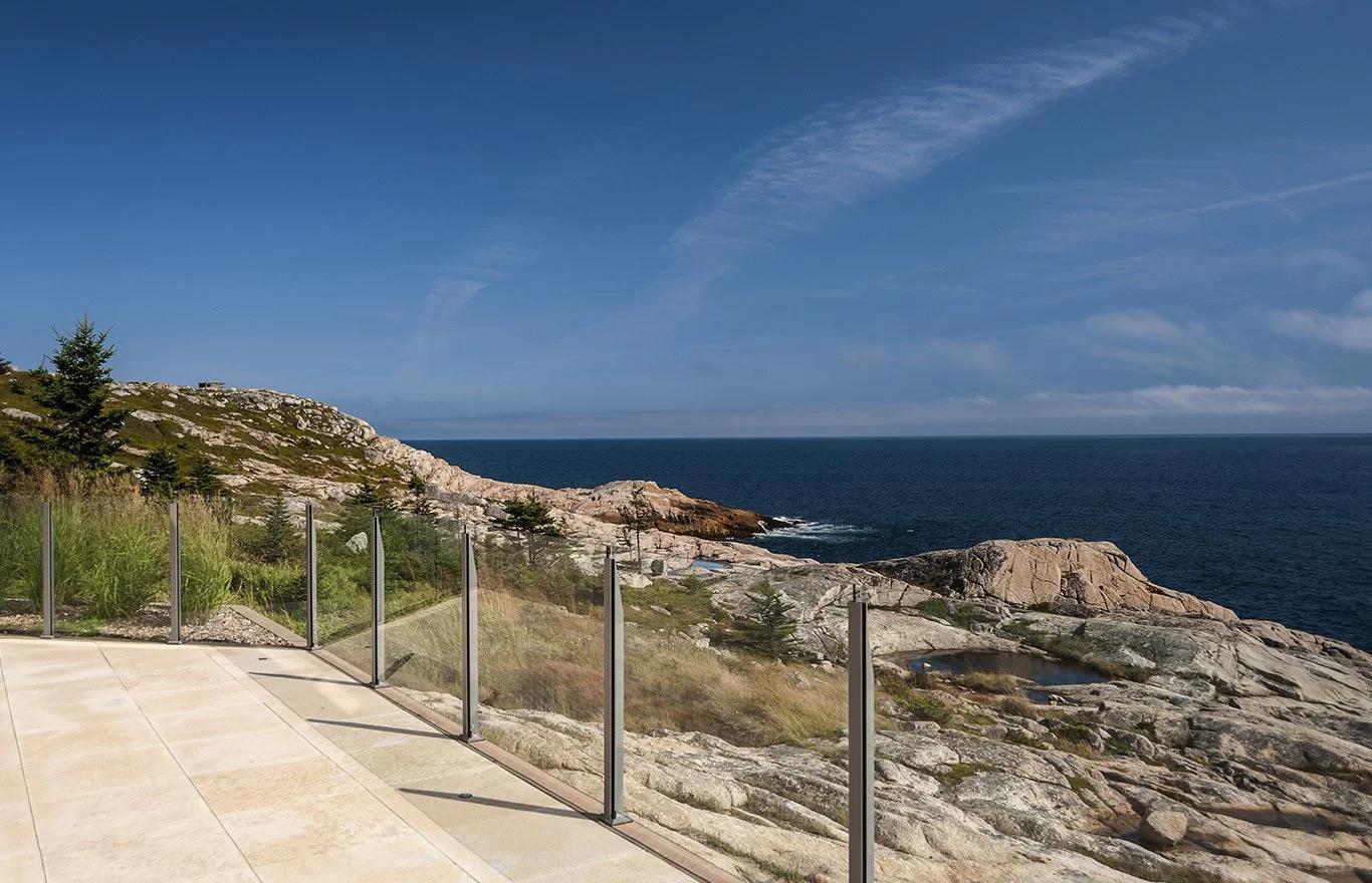  Infinity topless glass railing on a coastal property in Gill Cove, Nova Scotia, with aluminum posts and tempered glass panels exposed to Atlantic salt air
