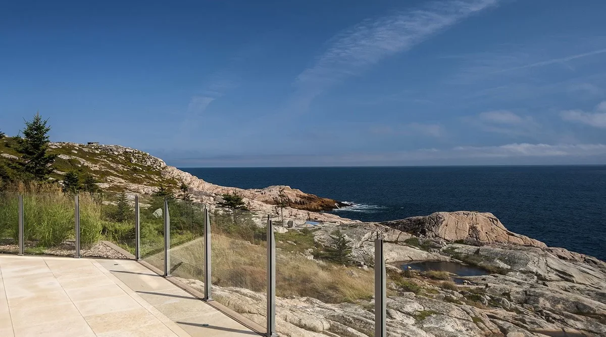 Infinity topless glass railing on a coastal property in Gill Cove, Nova Scotia, with aluminum posts and tempered glass panels exposed to Atlantic salt air