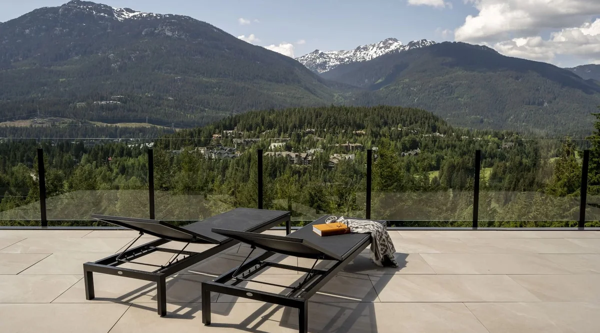 Frameless topless glass railing on a luxury Whistler BC deck with lounge chairs and unobstructed mountain views