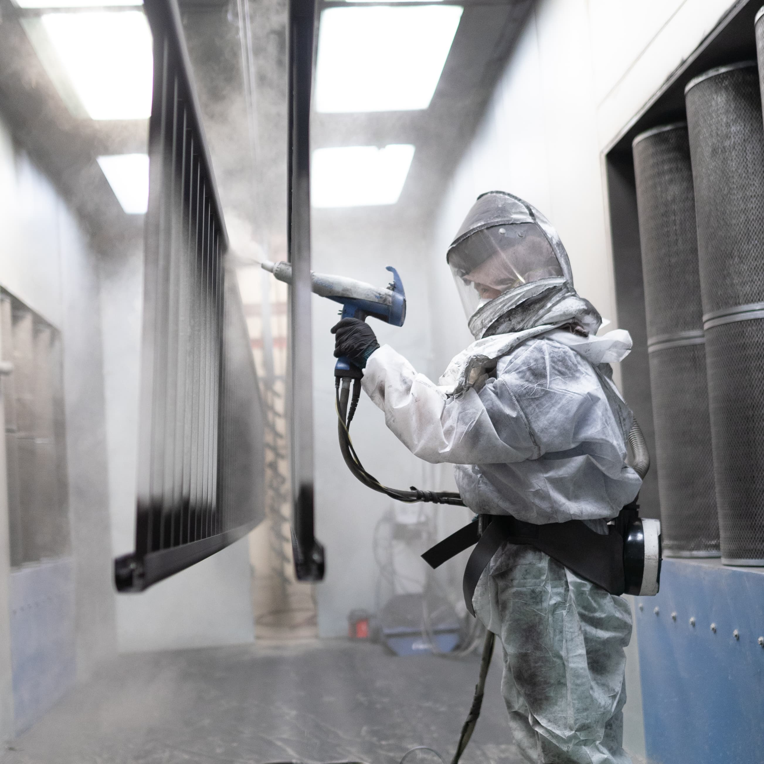 Electrostatic powder coating being applied to an aluminum railing panel in Innovative Aluminum's spray booth