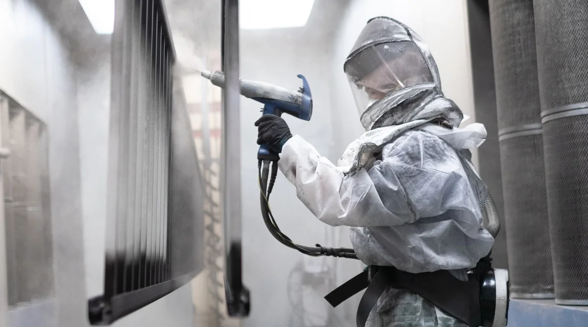 Electrostatic powder coating being applied to an aluminum railing panel in Innovative Aluminum's spray booth