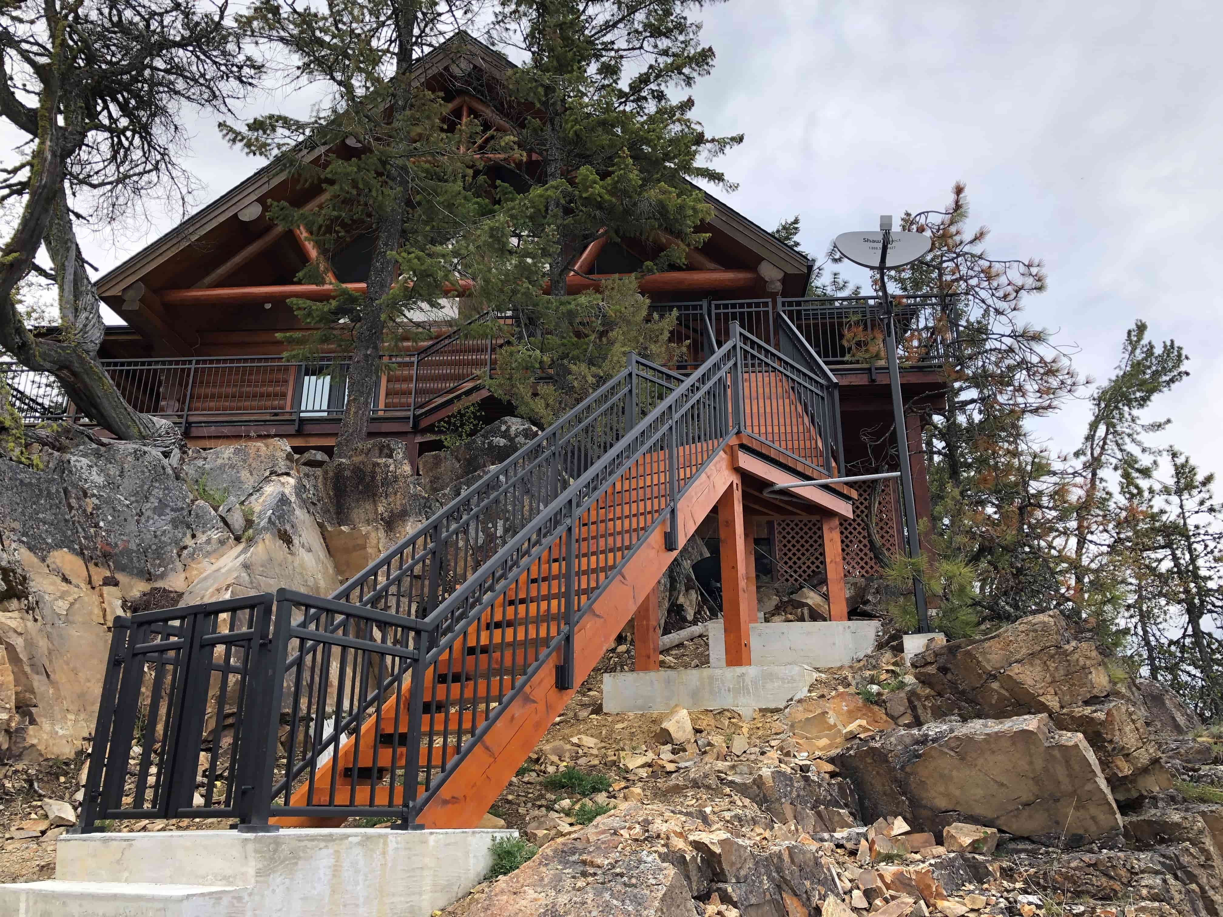 Textured black midrail picket aluminum railing on stairs and deck of a timber frame home in Christina Lake BC
