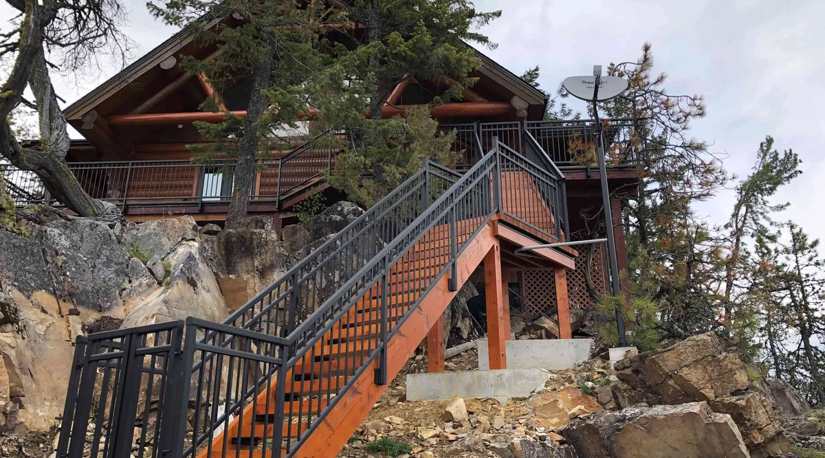 Textured black midrail picket aluminum railing on stairs and deck of a timber frame home in Christina Lake BC