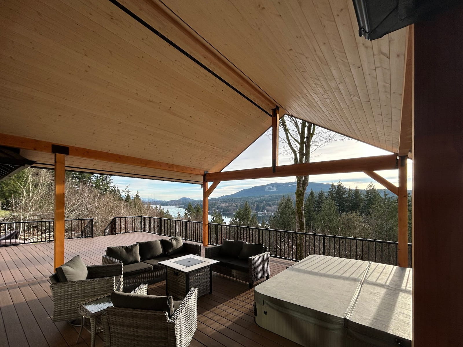 Black aluminum picket railing surrounding a covered deck with hot tub and lounge seating overlooking mountains and water in Bellingham, Washington