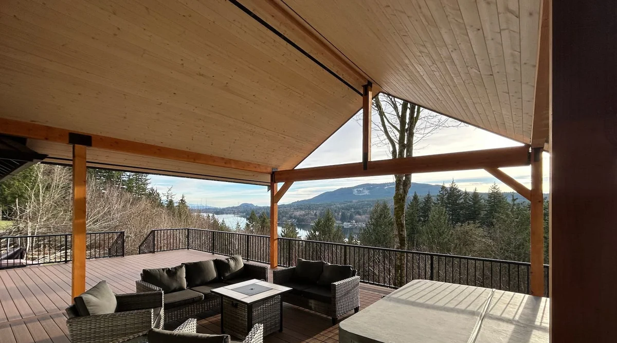 Black aluminum picket railing surrounding a covered deck with hot tub and lounge seating overlooking mountains and water in Bellingham, Washington