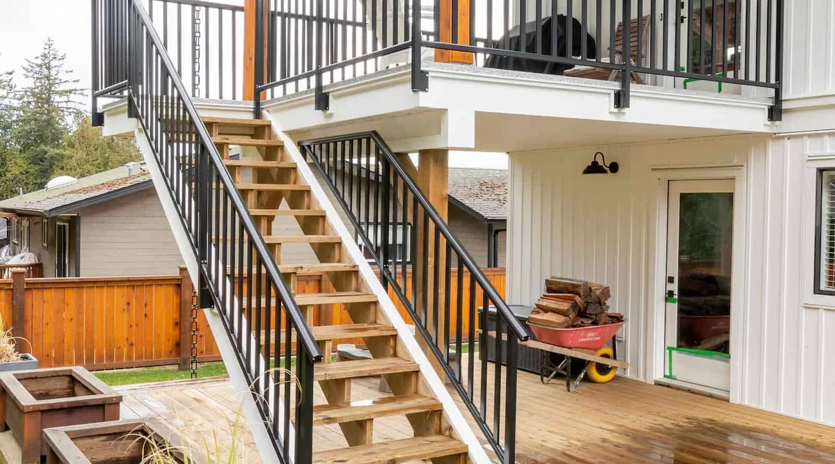 Black aluminum picket railing showing the stair-to-deck transition with colonial top rail on stairs for graspability code compliance in Powell River, BC