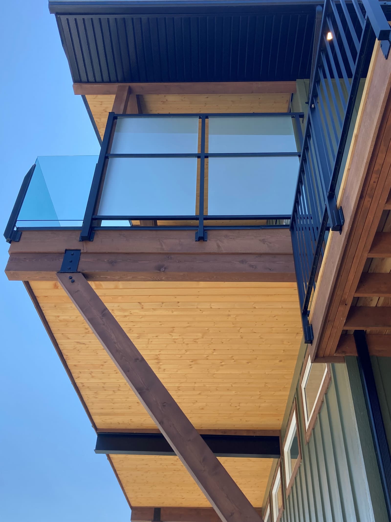 Frosted glass privacy screen panels with double glass mid-rail system on a balcony at a Christina Lake BC property viewed from below