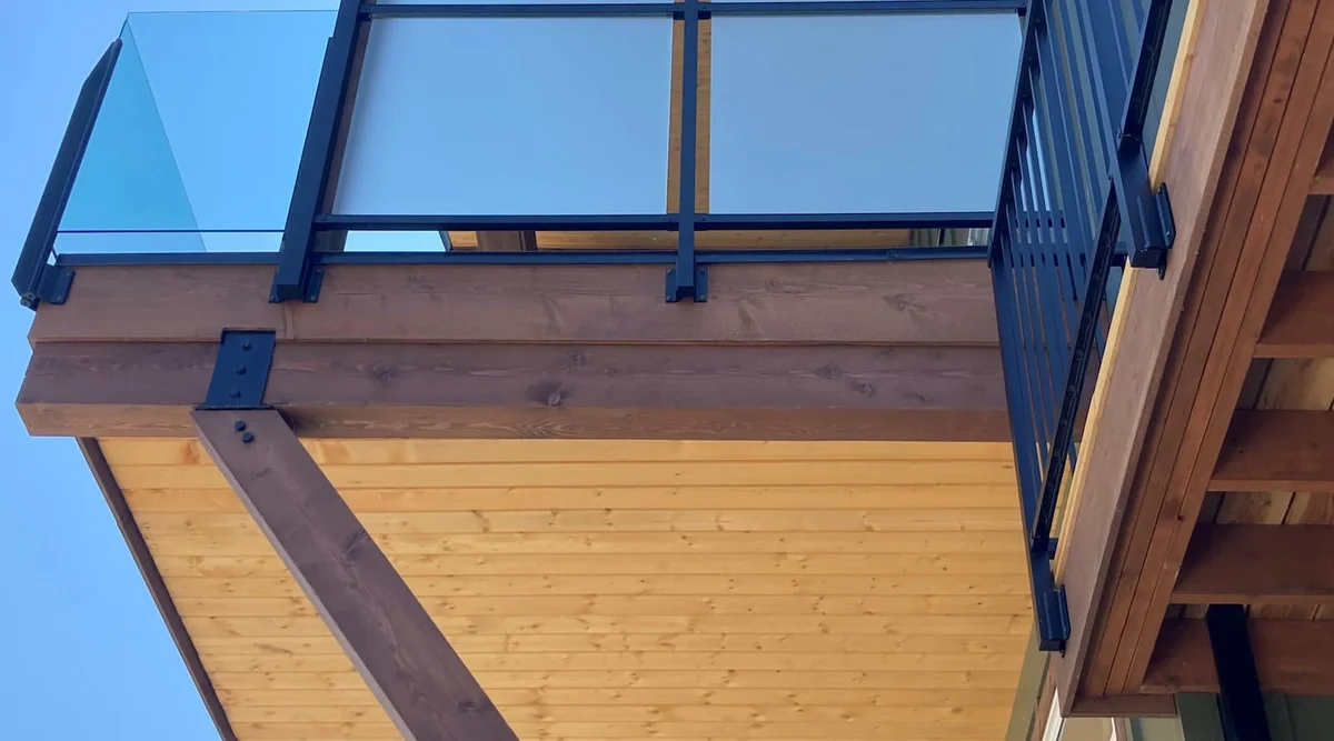 Frosted glass privacy screen panels with double glass mid-rail system on a balcony at a Christina Lake BC property viewed from below
