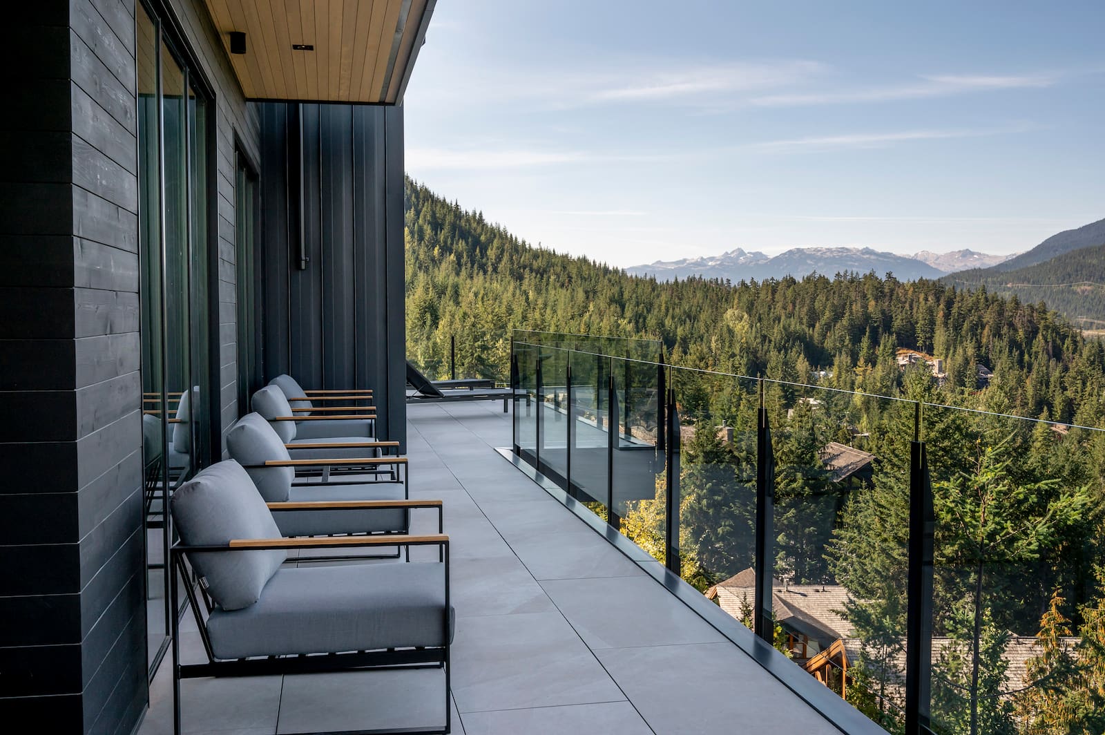 Fascia mount topless glass railing with black powder coated posts on a luxury balcony in Whistler BC with mountain views