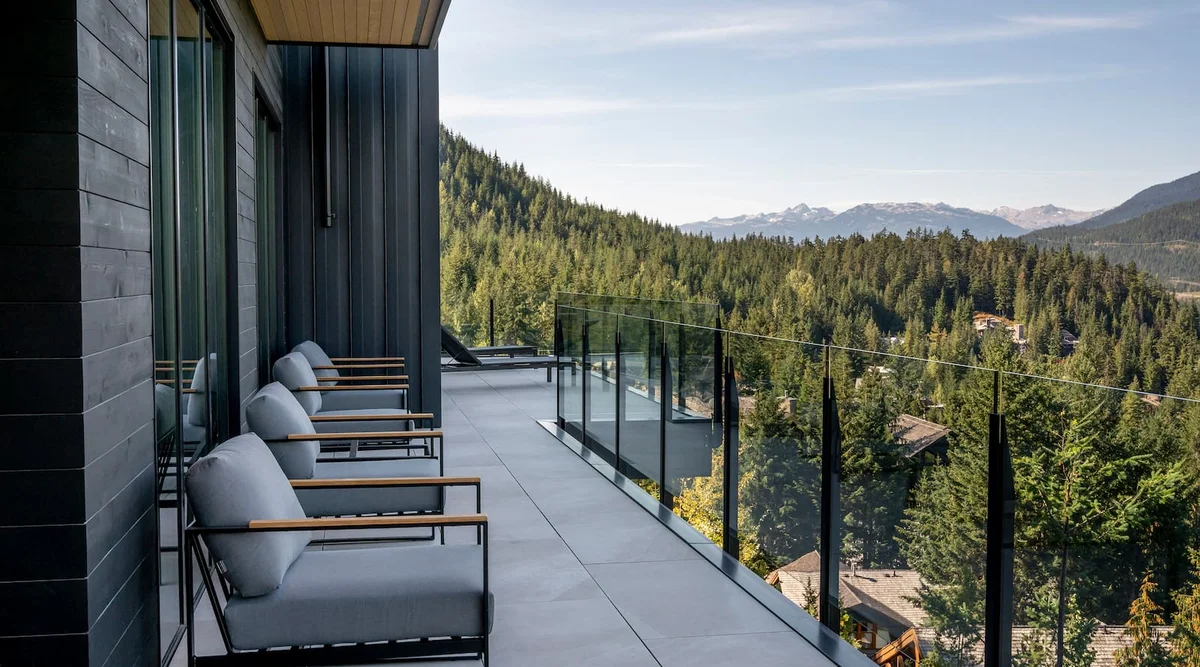 Fascia mount topless glass railing with black powder coated posts on a luxury balcony in Whistler BC with mountain views