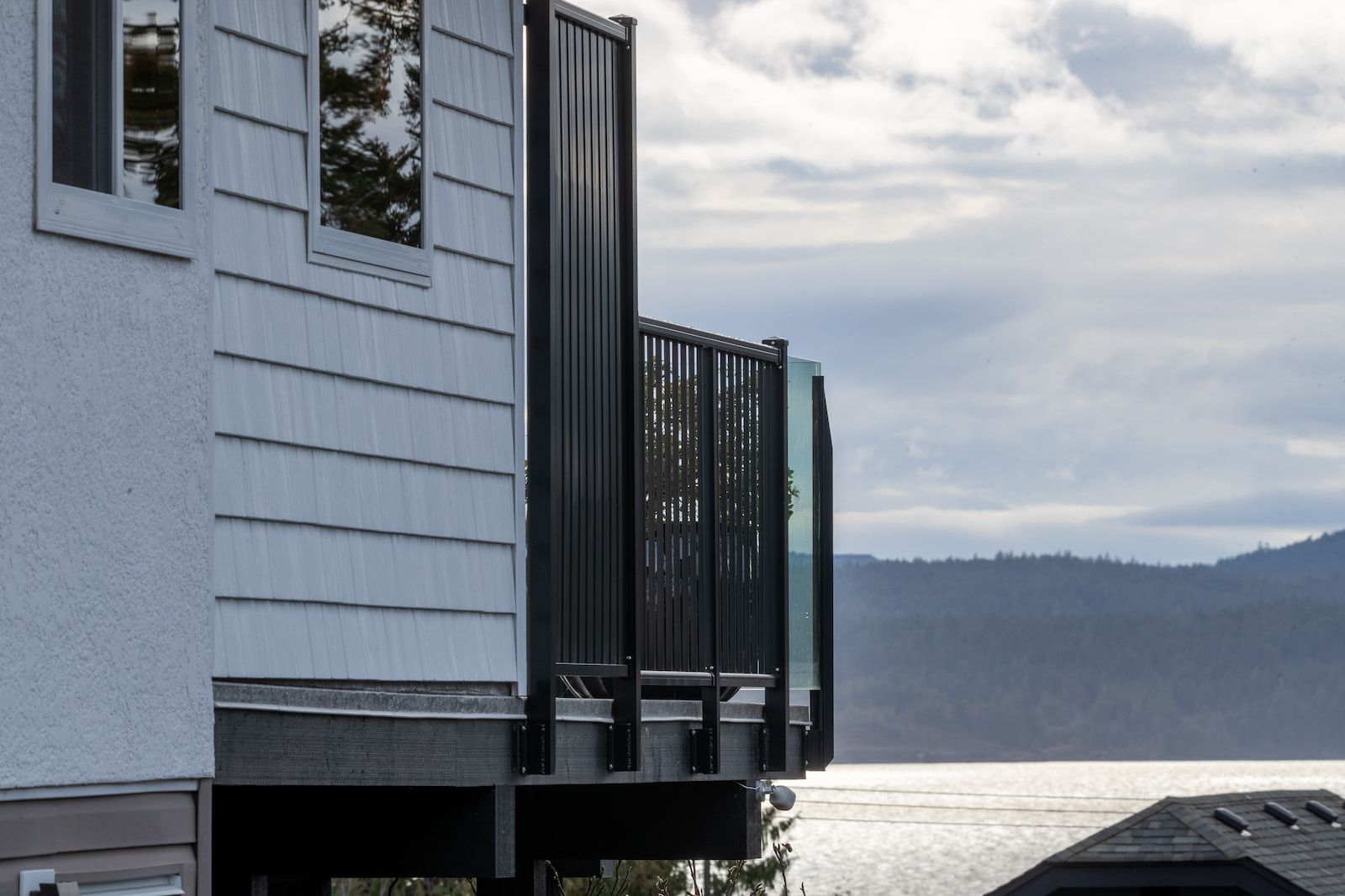 Black aluminum privacy picket panel screening a lakeview deck with frameless glass railing on the view side