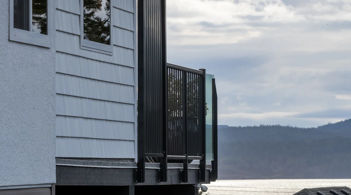 Black aluminum privacy picket panel screening a lakeview deck with frameless glass railing on the view side