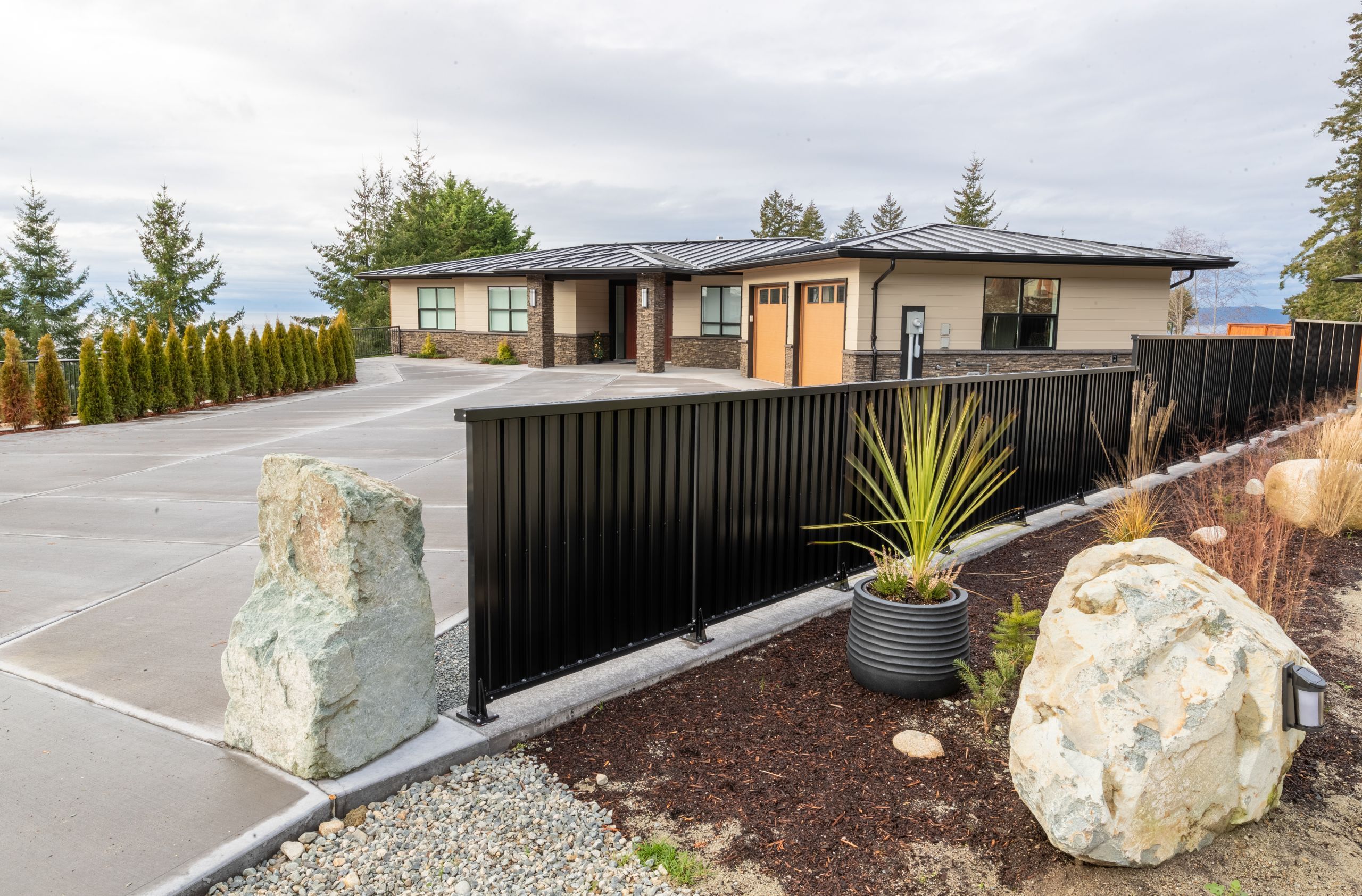 Black powder coated aluminum picket fencing along a driveway at a modern residential property in British Columbia