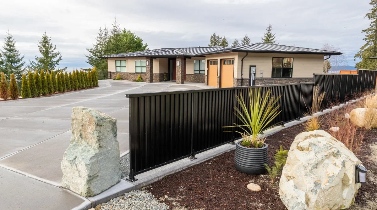 Black powder coated aluminum picket fencing along a driveway at a modern residential property in British Columbia
