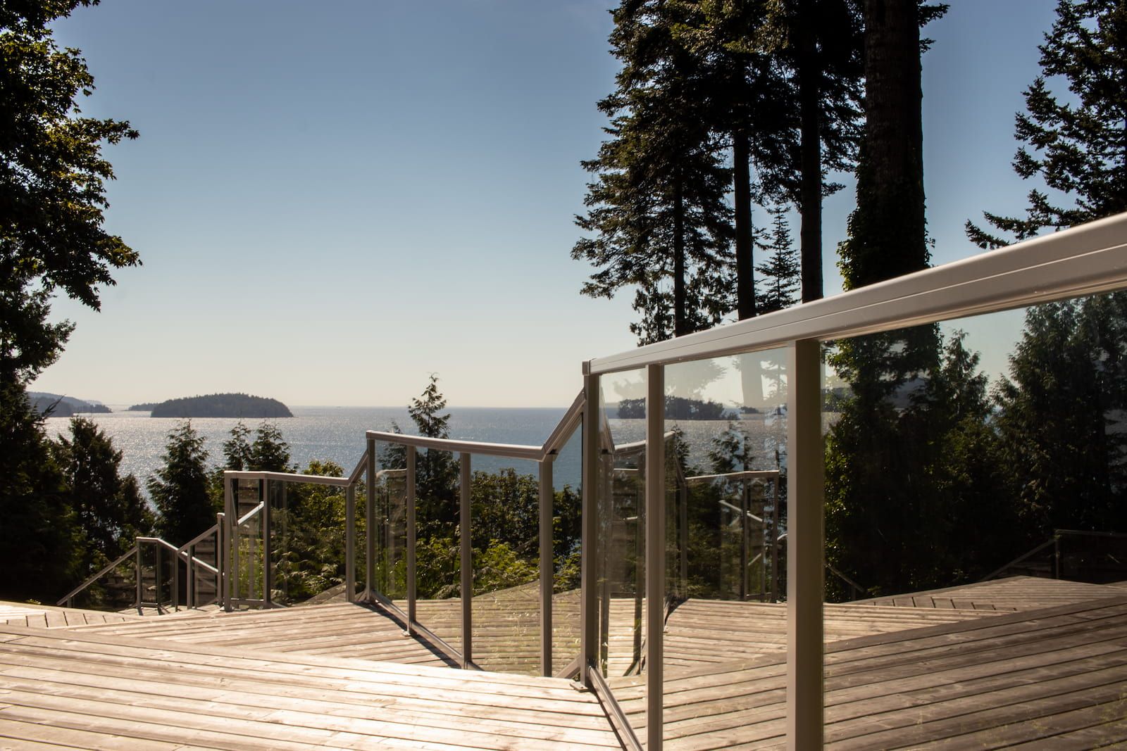Glass component railing in Silver Matte on a multi-level wood deck with stair transitions overlooking the BC coast