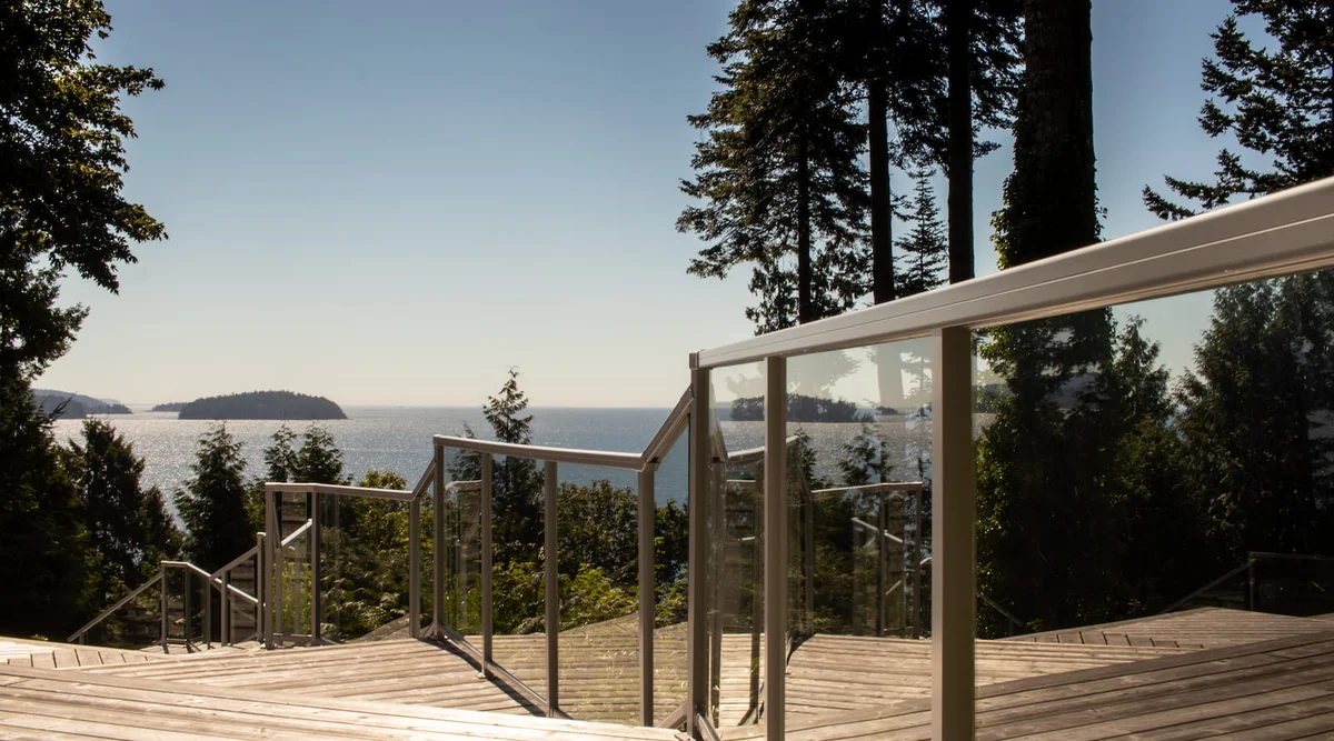 Glass component railing in Silver Matte on a multi-level wood deck with stair transitions overlooking the BC coast