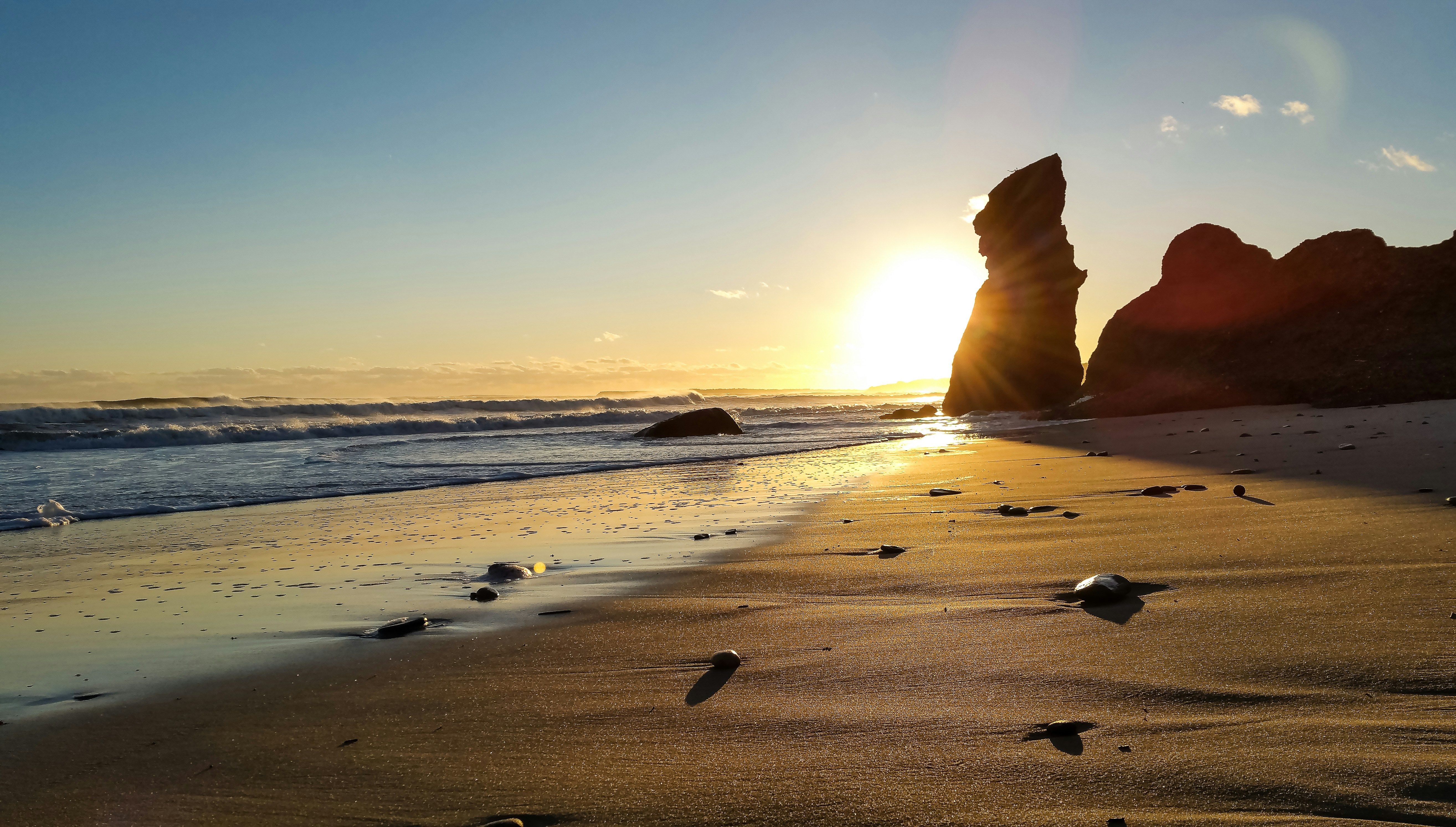 Aerial view of a white yacht sailing on deep blue sea near rocky coastline.