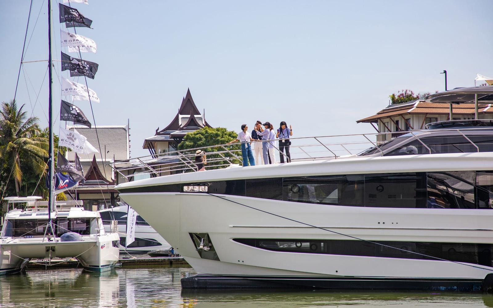 Modern yacht docked at marina with clear blue water and sky.