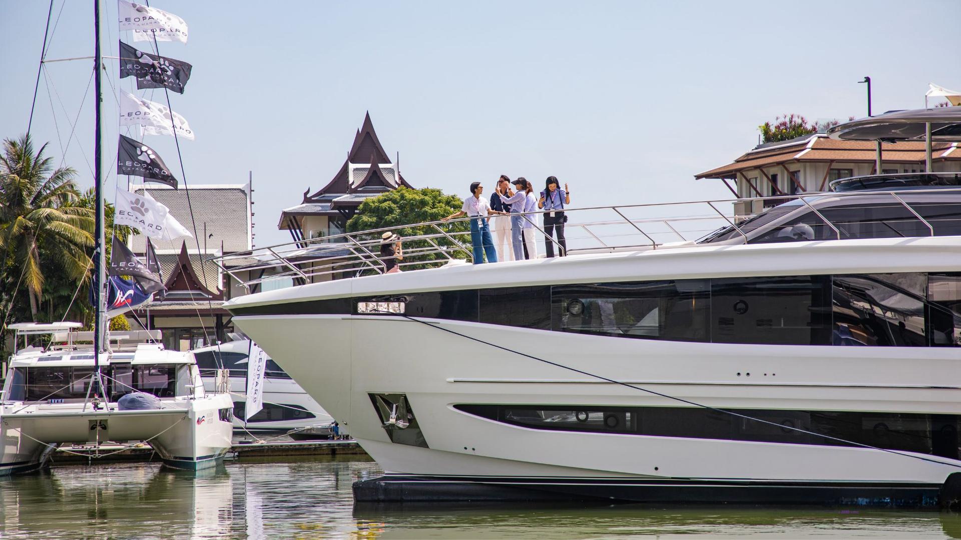 Modern yacht docked at marina with clear blue water and sky.