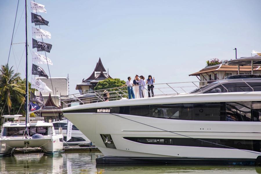 Modern yacht docked at marina with clear blue water and sky.