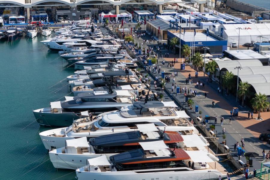 Modern luxury yacht anchored near a scenic coastal town with clear blue skies.