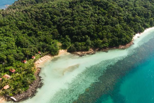 Yacht sailing near rocky coast.