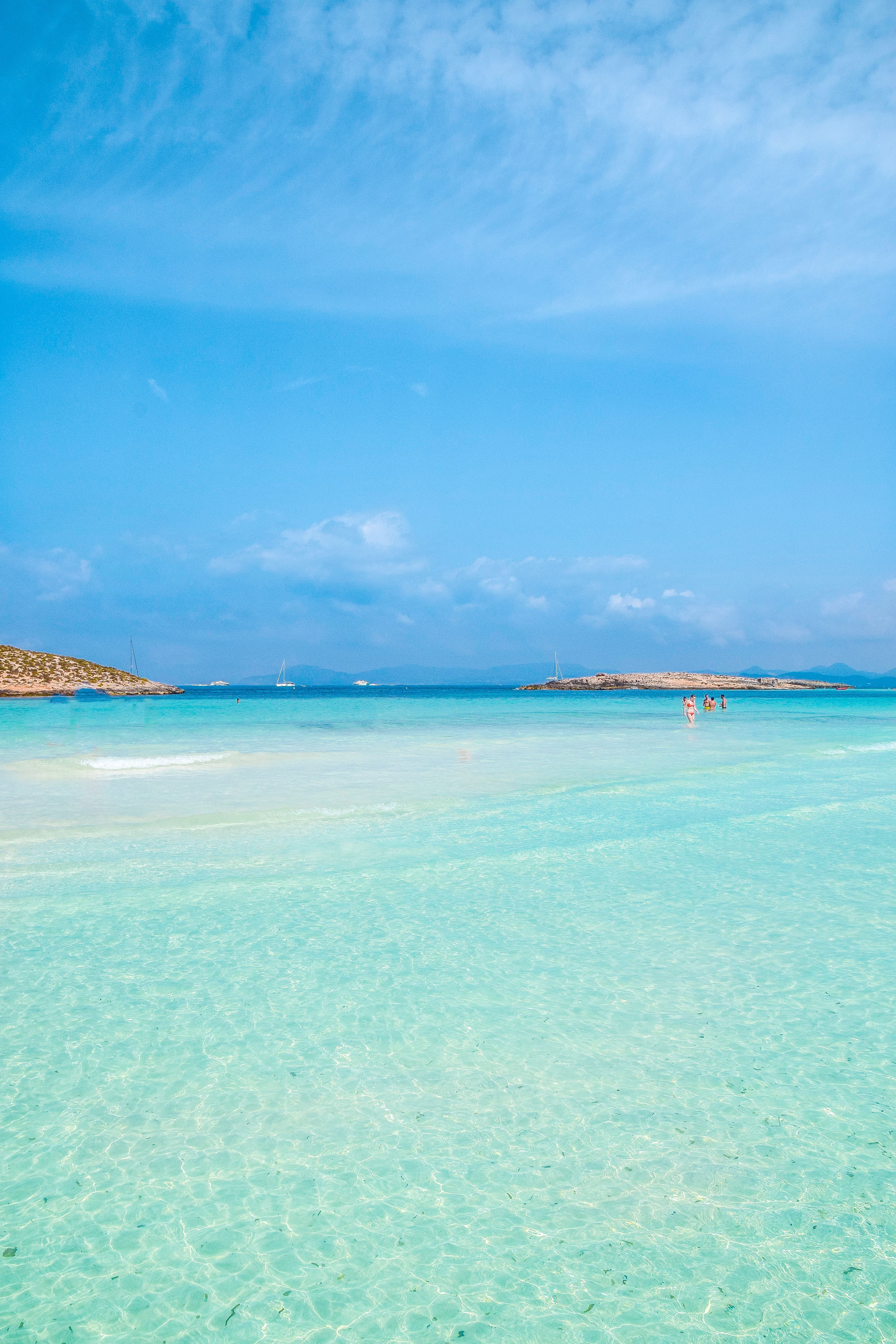 Crew member holding a tray with refreshments, smiling under the sun on a yacht deck.