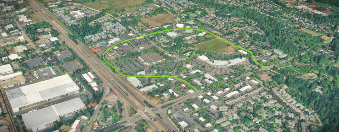 Aerial view of an urban area with a green outline around a mixed-use development next to a highway.