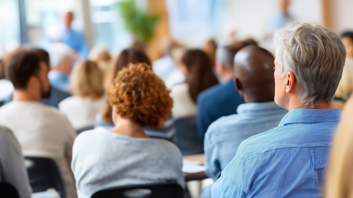 Diverse audience viewed from behind, attending a presentation.