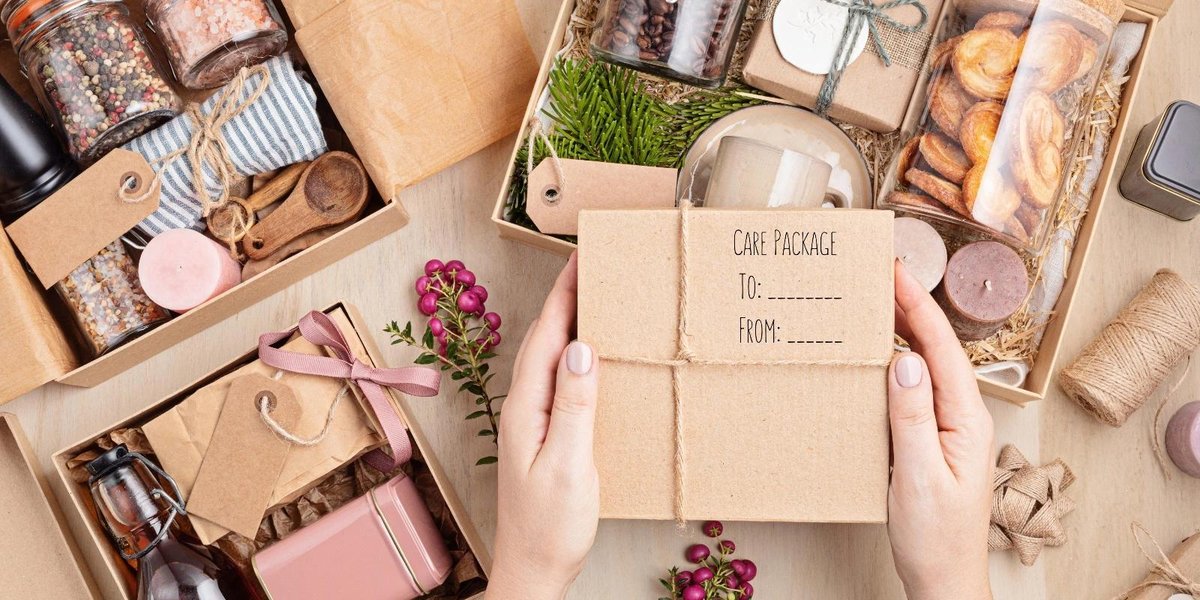Hands holding a Thanksgiving care package with assorted gifts for deployed troops.