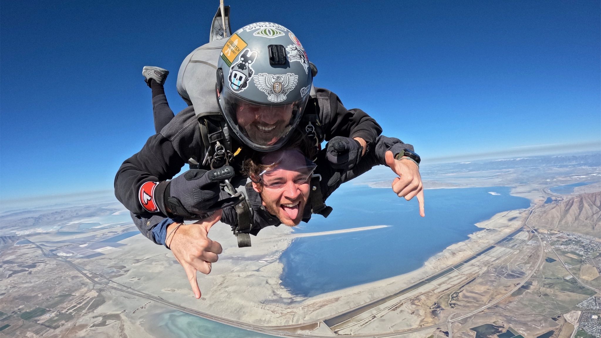 Two skydivers are attached and in midair.