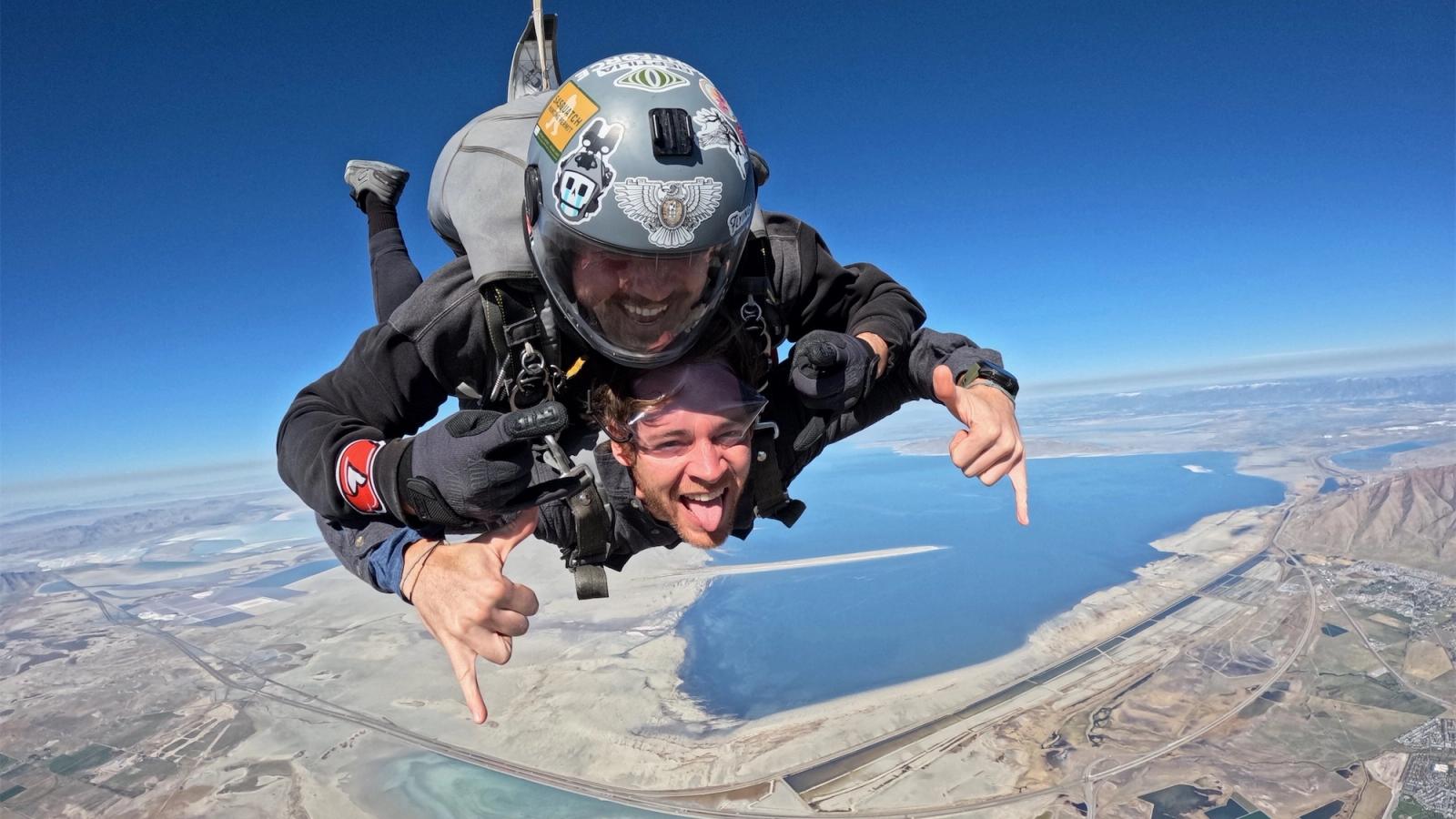 Two skydivers are attached and in midair.