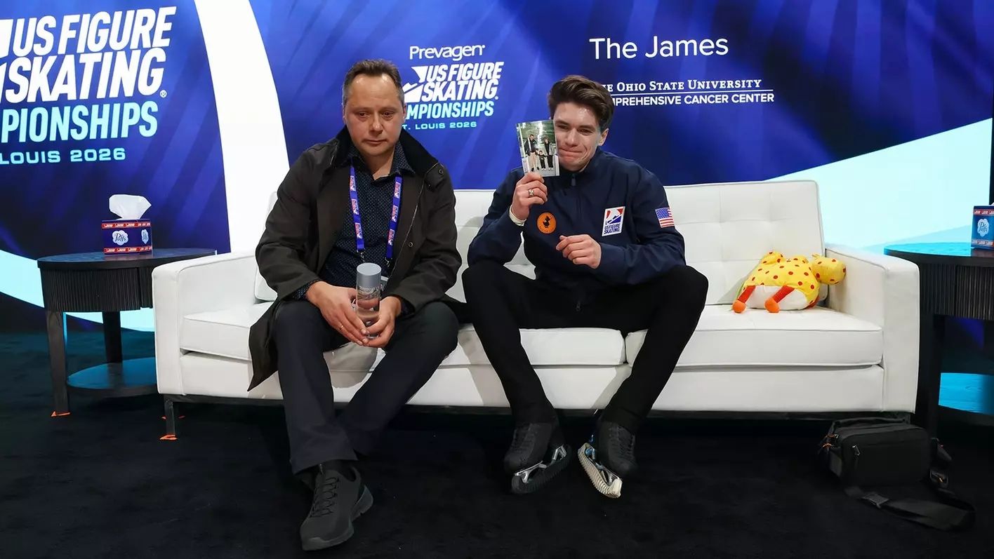 Athlete is sitting with his coach, holding a photo of himself and parents.