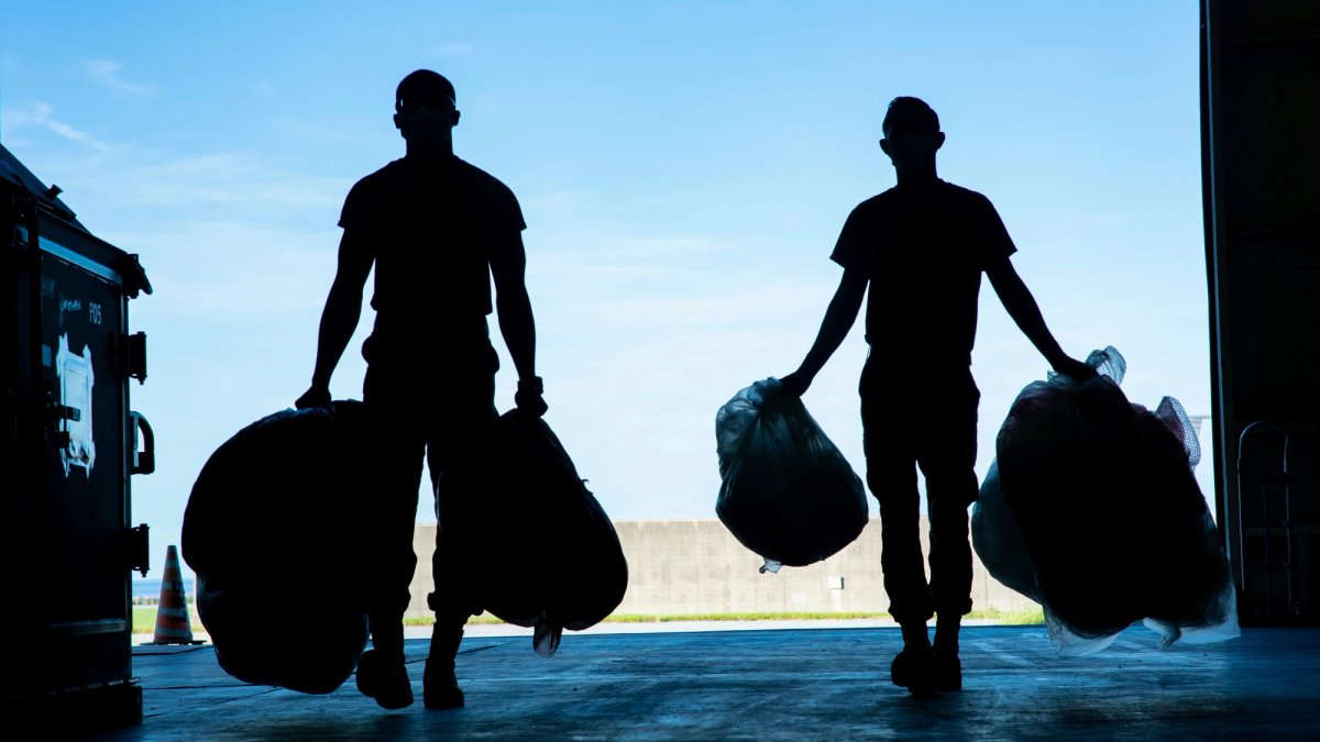 Silhouette of two soldiers holding heavy baggage.