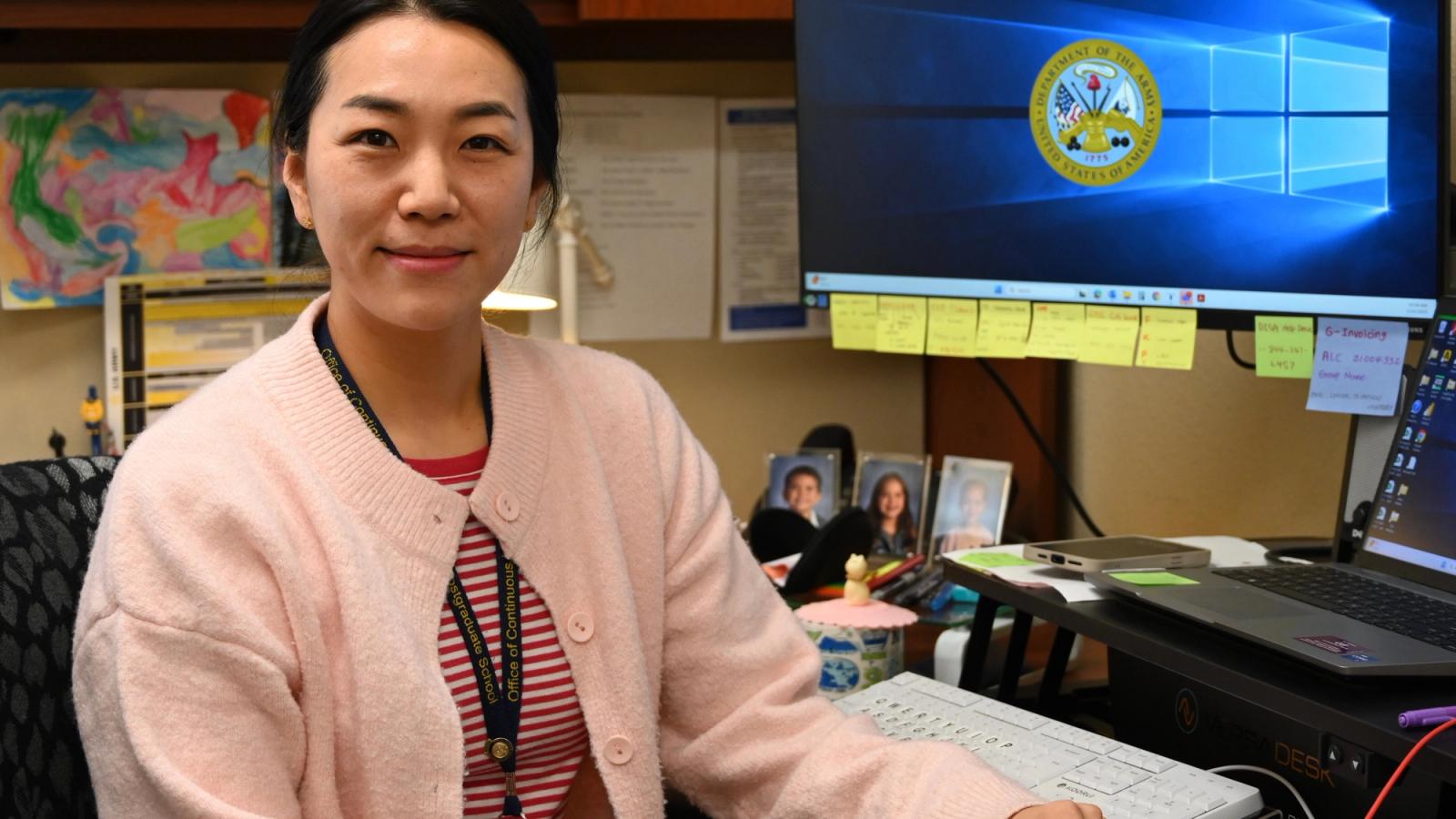 A budget analyst who is a military spouse sits at a desk.