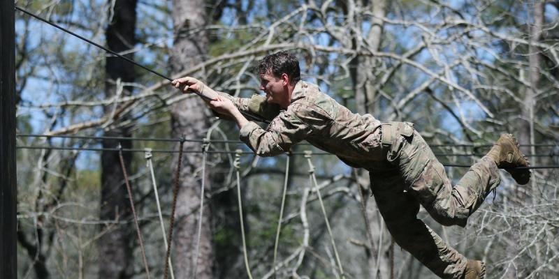 A student assigned to the U.S. Army John F. Kennedy Special Warfare Center and School climbs across a rope during the evasion phase of Survival Evasion Resistance and Escape Level-C training (SERE) at Camp Mackall, North Carolina, March 21, 2020.