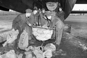 Vintage photo of servicemen uploading food from an airplane.