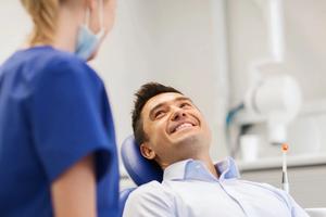 Man sitting in a chair smiles at his dentist.