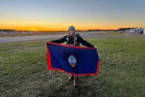 Female vet stands in an airfield holding a flag.