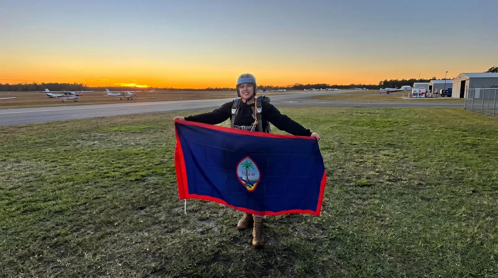 Female vet stands in an airfield holding a flag.