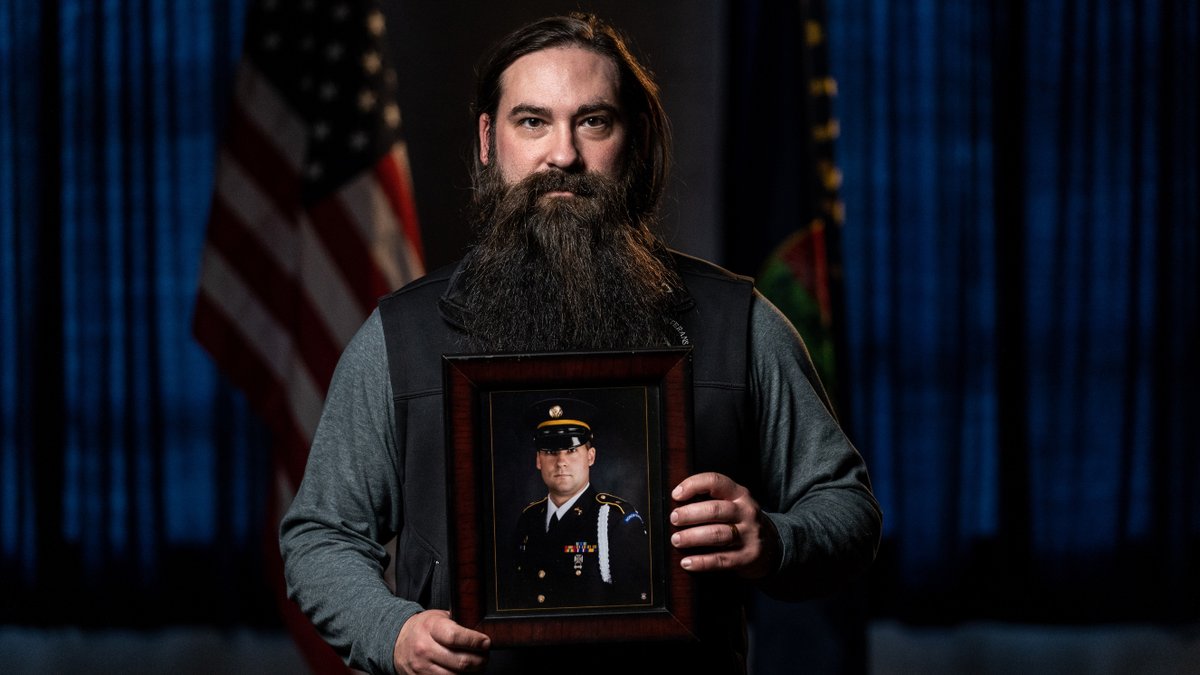 Chris Enget holds a photo of himself in uniform.
