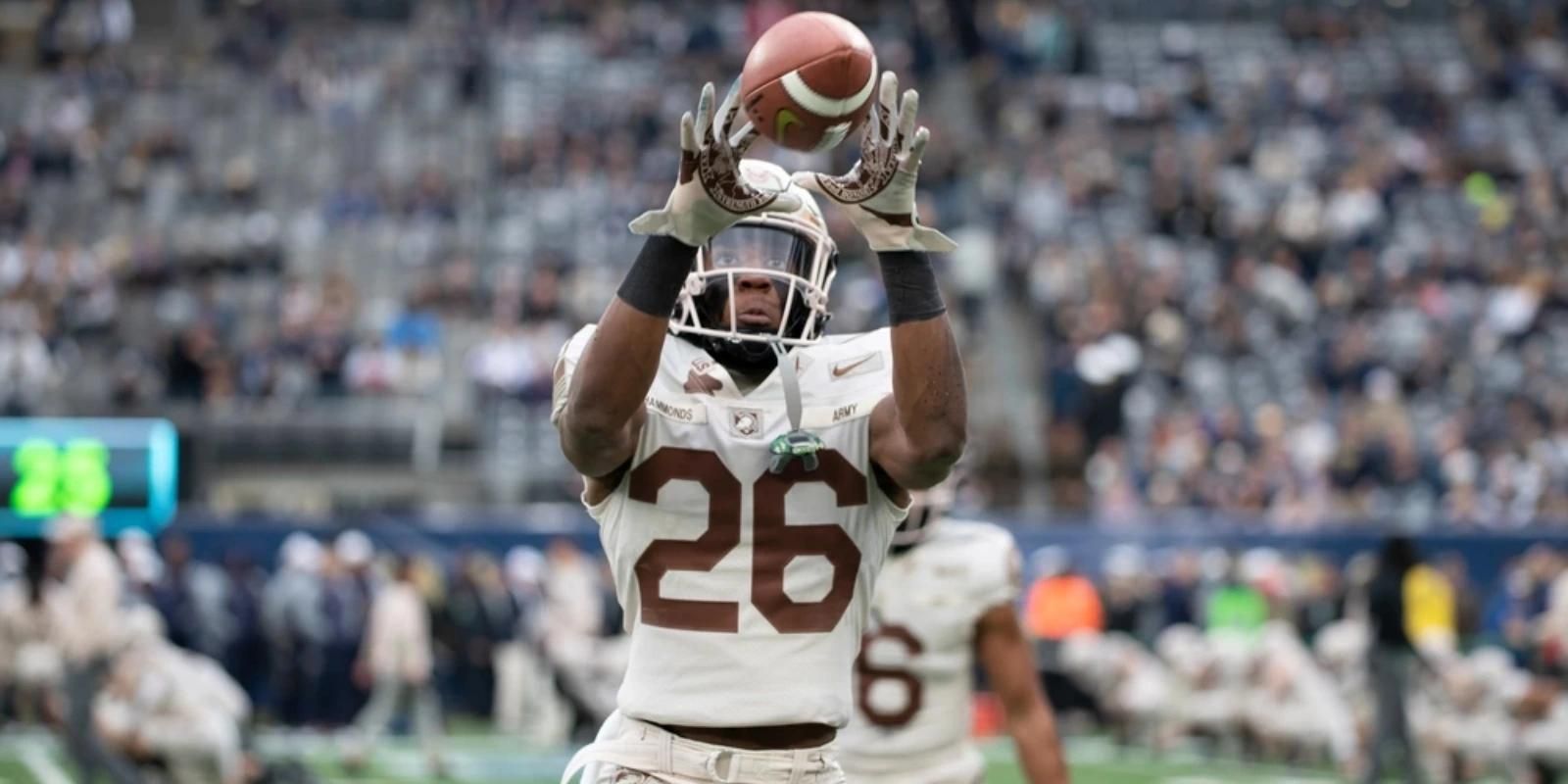 Army football player catching a pass during Army-Navy game on a stadium field