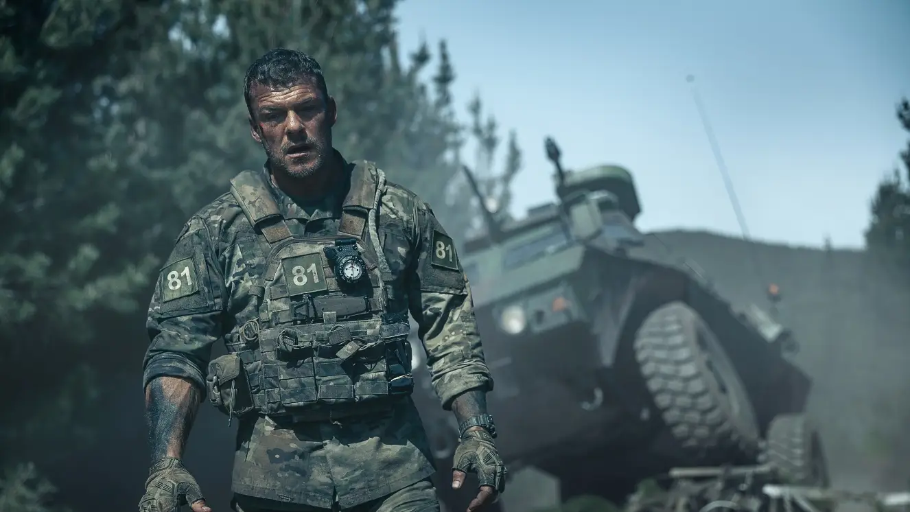 Soldier walks next to a tank.