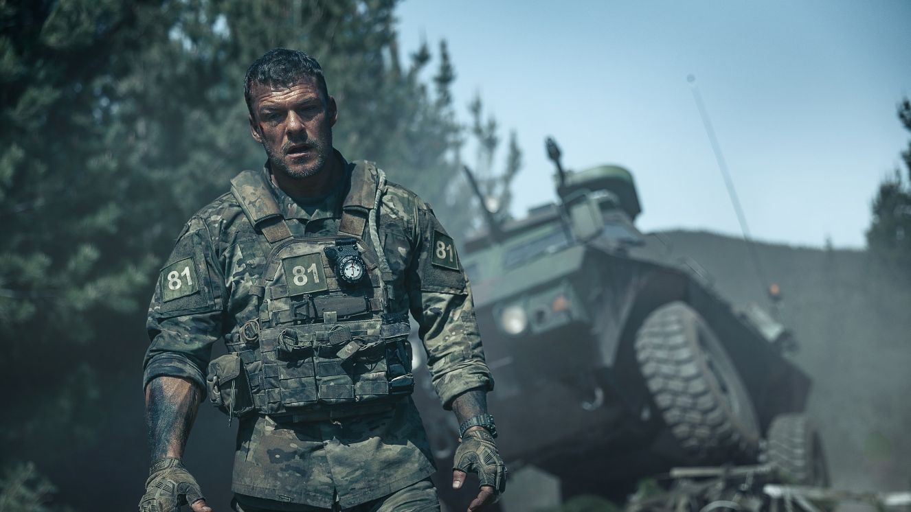 Soldier walks next to a tank.