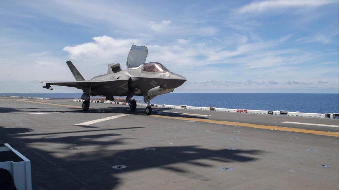 F-35 fighter jet on aircraft carrier deck at sea under clear sky