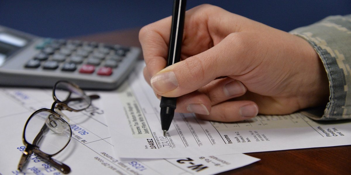 Uniformed hand fills out a tax form.