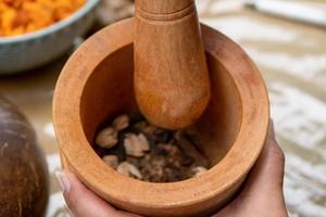 Dried iboga is crushed with a mortar and pestle.